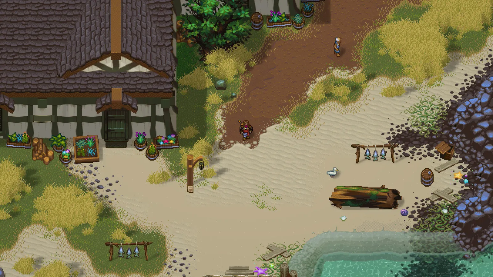 A daytime top-down view of a village with half-timber houses, dirt paths, wooden posts with banners, and water at the lower edge.